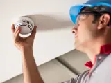 Person with PPE screwing in a smoke detector