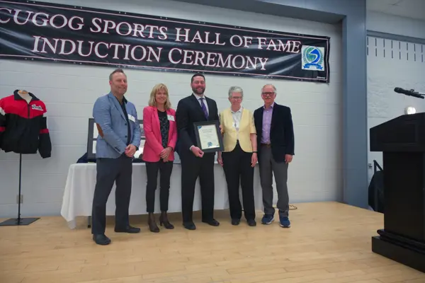 man being presented with award by four others