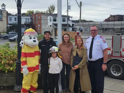 Junior Fire Chief Mia Soutar in front of Municipal Office with parents, Fire Chief Mark Berney, Councillor Guido, and Sparky the Fire Dog