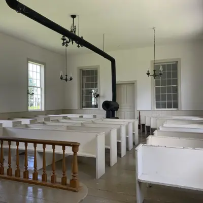 rows of white bench seats with brown railing in the front